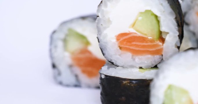 One or more maki rolls in a row with salmon, avocado, tuna and cucumber isolated on white background. Fresh hosomaki pieces with rice and nori. Closeup of delicious japanese food with sushi roll.