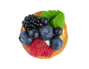 Tartlet with berries of raspberry, bilberry, blackberry, blueberry isolated on white background. Cake with berries, mint leaf and cheese cream. View from above
