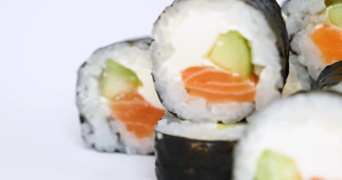 One or more maki rolls in a row with salmon, avocado, tuna and cucumber isolated on white background. Fresh hosomaki pieces with rice and nori. Closeup of delicious japanese food with sushi roll.