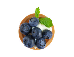 Macro photo of tartlets with bilberry, blueberries and mint leaves isolated on white background. Cakes with cheese cream and fresh blueberries. View from above