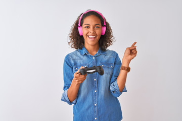 Brazilian gamer woman playing video game using headphones over isolated white background very happy...