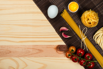 Naklejka premium Composition with different types of pasta on pine wood background. Space for text.