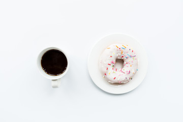 donut and black coffee with copy space. Cup of black coffee with donut on a plate on white table, top view, flat lay. Delicious breakfast.