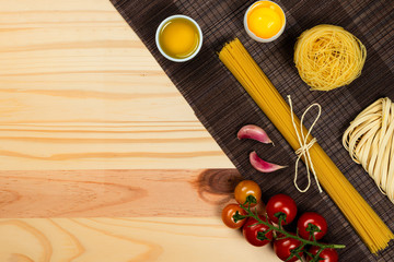 Composition with different types of pasta on pine wood background. Space for text.