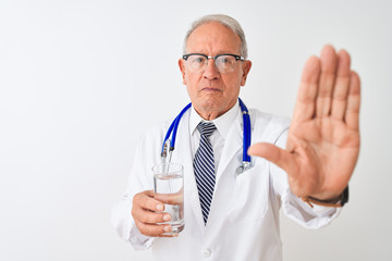 Senior grey-haired doctor man drinking glass of water over isolated white background with open hand doing stop sign with serious and confident expression, defense gesture