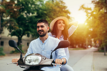 Happy couple on scooter driving outdoor in the city