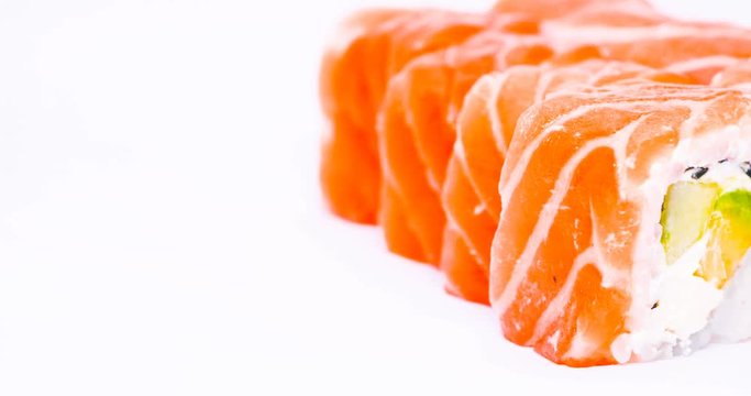 One or more maki rolls in a row with salmon, avocado, tuna and cucumber isolated on white background. Fresh hosomaki pieces with rice and nori. Closeup of delicious japanese food with sushi roll.
