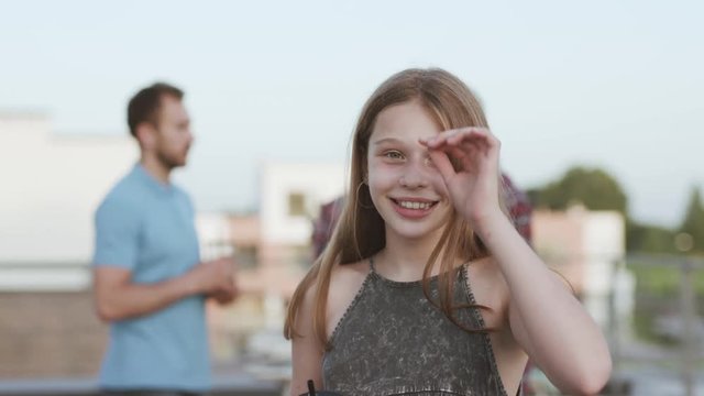 Outdoor portrait of adorable happy girl teenager smiling happy celebrating moving house party with her family on the terrace.