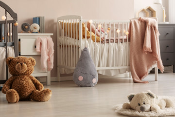 Cute plush toys and pink blankets in cozy bedroom interior for twin girls with two cribs and...