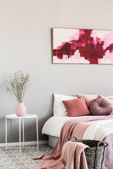 Abstract white and burgundy painting on the wall of stylish bedroom interior with king size bed
