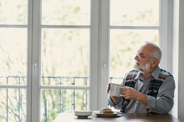 Melancholic grandfather eating breakfast all alone at the table