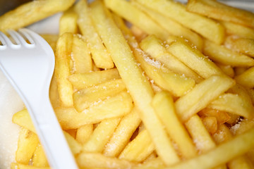 French fries with salt and plastic white fork.