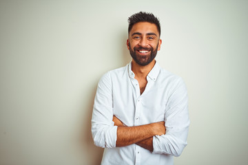 Young indian man wearing elegant shirt standing over isolated white background happy face smiling with crossed arms looking at the camera. Positive person. - Powered by Adobe