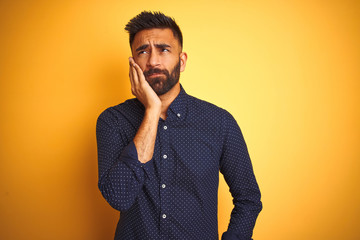 Young handsome indian businessman wearing shirt over isolated yellow background thinking looking tired and bored with depression problems with crossed arms.