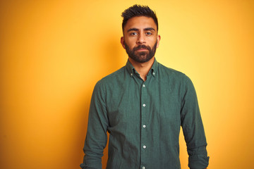 Young indian businessman wearing elegant shirt standing over isolated white background Relaxed with serious expression on face. Simple and natural looking at the camera.