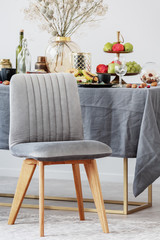 Trendy grey chair in front of dining room table full of food