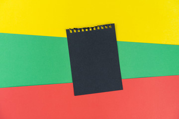Black list Lithuania. Mourning, ban, sanctions. black sheet of notepad is on Lithuanian flag. Mock up, copy space, pattern, cardboard texture.