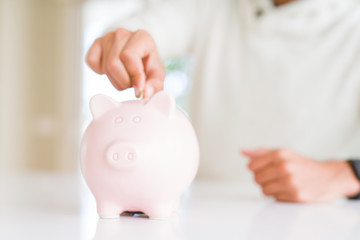 Man putting a coin inside of piggy bank saving for investment