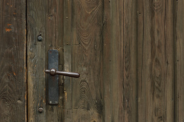 Background with an old brown, closed and weathered wooden door and doorknob