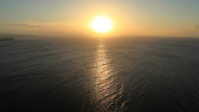 View of sunset over sea and waves hitting coastline, Guam