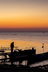Silhouettes of fishermen and boats at the Port of Ahtopol, Black Sea Coast, Bulgaria at sunrise