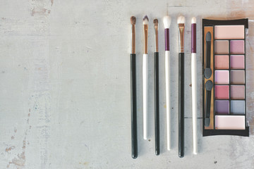 Eye shadows palette with a makeup brushes on a white wooden table background with a copy space.