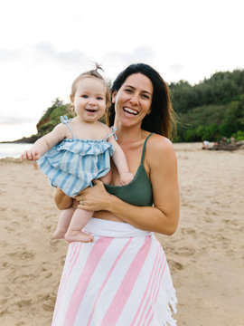 Woman holding baby daughter at beach