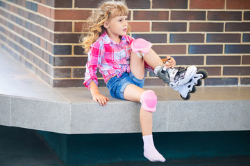 Little pretty girl on roller skates at a park. Cheerful preschool girl wearing inline roller skates...