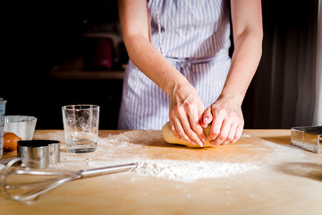 Fototapeta na wymiar women's hands knead the dough on the table, kitchen accessories