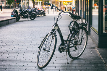 Fototapeta na wymiar Bicycle black color parked on a sidewalk in Rotterdam city, Netherlands