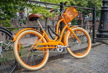 Fototapeta na wymiar Yellow bike color locked on a river canal rail in Utrecht city, Netherlands