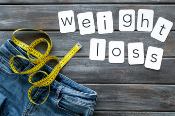 Trousers with measuring tape and weight loss concept for sport concept on wooden background top view