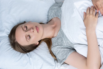 top view of young woman sleeping in bed under blanket