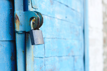 old padlock on a blue metal door with wooden planks cracked paint and rust