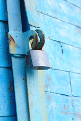old padlock on a blue metal door with wooden planks cracked paint and rust