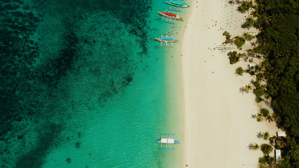 Aerial seascape: Tropical beach with palm trees and turquoise waters of the coral reef, from above, Puka shell beach. Boracay, Philippines. Seascape with beach on tropical island. Summer and travel