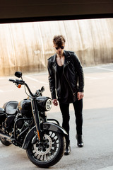 Fototapeta na wymiar handsome young man walking to garage to black motorcycle