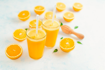 Top view of orange smoothie and orange fruits with green leaves on white background.