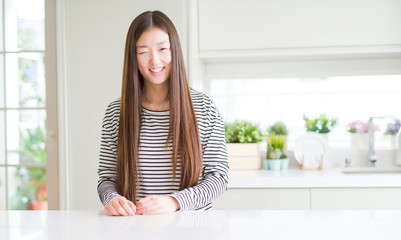 Beautiful Asian woman wearing stripes sweater winking looking at the camera with sexy expression,...