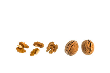 whole walnuts with halved walnut kernels on white background with copy space above
