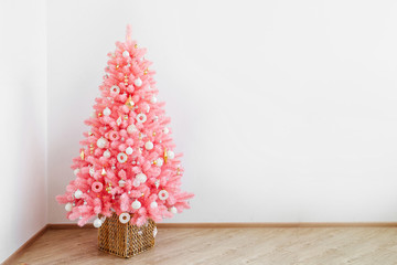 Pink christmas tree and christmas decorations white and gold color in white interior