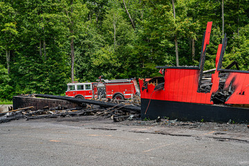 Big red fire truck near the burnt out shop, fire extinguished.