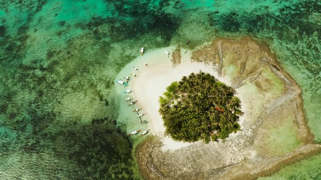 Aerial view of sandy beach with tourists on tropical island with palm trees and turquoise water. Guyam island, Philippines, Siargao. Summer and travel vacation concept