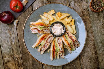 club sandwich with fries on wooden table