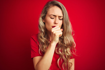 Young beautiful woman wearing basic t-shirt standing over red isolated background feeling unwell and coughing as symptom for cold or bronchitis. Healthcare concept.