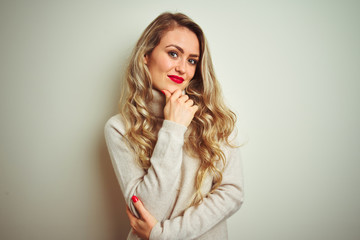 Beautiful woman wearing winter turtleneck sweater over isolated white background looking confident at the camera smiling with crossed arms and hand raised on chin. Thinking positive.