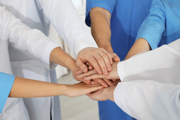 Team of medical workers holding hands together, closeup. Unity concept