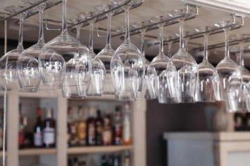 Set of empty clean glasses on bar racks