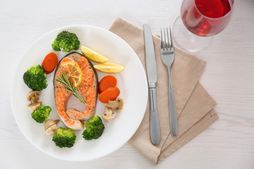 Plate with salmon steak and garnish prepared in multi cooker on table, flat lay