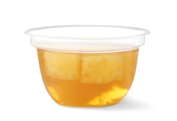 Tasty jelly dessert with slices of fruit in plastic cup on white background